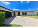 Beautiful home with a brick driveway, black accents, and a white exterior and dark trim at 13916 Wellesford Way, Tampa, FL 33624