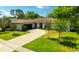 Beautiful, landscaped home with a brick driveway, green lawn, and inviting front yard with trees at 13916 Wellesford Way, Tampa, FL 33624