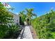 A stone path with verdant, tropical landscaping and bright blue sky creates a welcoming atmosphere at 13916 Wellesford Way, Tampa, FL 33624
