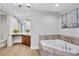 Relaxing bathroom with soaking tub, wood cabinets, and decorative art at 140 Riviera Dunes Way # 1203, Palmetto, FL 34221