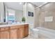 Well-lit main bathroom with wood cabinets, a walk-in shower with neutral tiling and a coastal motif at 140 Riviera Dunes Way # 1203, Palmetto, FL 34221