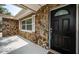 Close-up of black front door with stone accents and modern seating on front porch at 1402 Oleander Dr, Tarpon Springs, FL 34689
