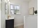 Chic bathroom showcasing a black vanity with a gold faucet, complemented by a window and sleek tile design at 1404 E Curtis St, Tampa, FL 33603