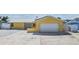 Yellow home featuring a metal roof, solar panels, and a white garage door with concrete driveway at 1421 Sea Gull S Dr, St Petersburg, FL 33707