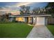 Well-maintained single-story home with lush green lawn and inviting curb appeal at dusk at 14626 Wildwood Dr, Largo, FL 33774