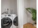 Modern laundry room with side-by-side washer and dryer and palm houseplant at 14626 Wildwood Dr, Largo, FL 33774