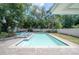 Private backyard featuring a pool, sun loungers, and mature tropical landscaping at 14626 Wildwood Dr, Largo, FL 33774