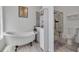 White bathroom with clawfoot tub, shelving, glass shower, and modern toilet at 1472 Bay View St, Tarpon Springs, FL 34689