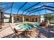 Screened-in pool area with a jacuzzi, a rock waterfall feature, and lots of brick-paved patio space at 1521 Avondale Ridge Dr, Plant City, FL 33567