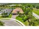 Aerial view of a well-manicured home, complete with a three-car garage, lush landscaping, and tiled roof at 15303 Valencia Del Sol St, Wimauma, FL 33598