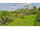 Landscaped backyard featuring a black fence, green lawn, and flowering plants at 15303 Valencia Del Sol St, Wimauma, FL 33598