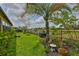Well-maintained backyard with green grass, black fence, and mature palm trees at 15303 Valencia Del Sol St, Wimauma, FL 33598