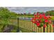 Lawn with flowers along a pond, as seen from behind a black metal fence at 15303 Valencia Del Sol St, Wimauma, FL 33598