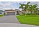 Charming home with a manicured lawn, colorful flowerbeds, paver driveway, and a two car garage at 15303 Valencia Del Sol St, Wimauma, FL 33598