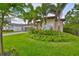 Home exterior with lush front yard landscaping, green grass, and mature trees at 15303 Valencia Del Sol St, Wimauma, FL 33598