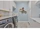 Well-organized laundry room with washer and dryer, cabinets, and herringbone tile floor at 15303 Valencia Del Sol St, Wimauma, FL 33598