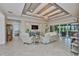 Inviting living room with tray ceiling, stone accent wall, tile floors, and sliding glass doors to the patio at 15303 Valencia Del Sol St, Wimauma, FL 33598
