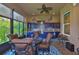 Enclosed outdoor kitchen with blue cabinets, stainless steel grill, and dining area with ceiling fan at 15303 Valencia Del Sol St, Wimauma, FL 33598