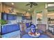 Covered outdoor kitchen with blue cabinets, stainless steel grill, and adjacent interior view at 15303 Valencia Del Sol St, Wimauma, FL 33598