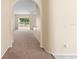 Hallway with arched doorways, carpeting, baseboard trim, and neutral walls with natural light at 1654 Portsmouth Lake Dr, Brandon, FL 33511