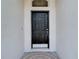 Close-up of a classic black front door framed by neutral-toned walls and a welcome mat at 19910 Wyndmill Cir, Odessa, FL 33556