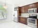 This kitchen features wood cabinets, stainless steel appliances, granite countertops, and white tile flooring at 19910 Wyndmill Cir, Odessa, FL 33556