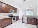This kitchen features wood cabinets, stainless steel appliances, granite countertops, and white tile flooring at 19910 Wyndmill Cir, Odessa, FL 33556