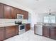 This kitchen features wood cabinets, stainless steel appliances, granite countertops, and white tile flooring at 19910 Wyndmill Cir, Odessa, FL 33556