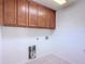 Practical laundry room with overhead cabinets, tile flooring, and visible utility connections at 19910 Wyndmill Cir, Odessa, FL 33556