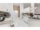 Bright kitchen featuring white cabinets, appliances, mosaic backsplash, and white tiled floors at 2015 W Del Webb Blvd, Sun City Center, FL 33573