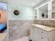 Bathroom vanity with framed mirror, granite countertop, and tiled backsplash at 230 Medallion Blvd # G, Madeira Beach, FL 33708