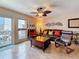 Living room with a ceiling fan, leather sofa, tile floors, and sliding doors to the balcony at 230 Medallion Blvd # G, Madeira Beach, FL 33708