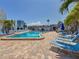 Bright outdoor pool with lounge chairs on a brick patio and palm trees at 230 Medallion Blvd # G, Madeira Beach, FL 33708