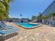 Outdoor pool with lounge chairs on a brick patio surrounded by palm trees at 230 Medallion Blvd # G, Madeira Beach, FL 33708