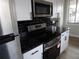 Updated kitchen featuring stainless steel appliances, black granite countertops, and white cabinets at 2699 Seville Blvd # 802, Clearwater, FL 33764