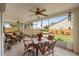 Enclosed patio featuring ceiling fans, tile flooring, and comfortable wicker furniture overlooking the landscaped backyard at 29713 Bright Ray Pl, Wesley Chapel, FL 33543