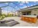 Screened-in lanai with a hot tub, patio furniture, and lush landscaping, perfect for outdoor living at 32231 Conchshell Sail St, Wesley Chapel, FL 33545