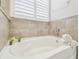 Clean white bathtub with tile surround and ambient decor at 32231 Conchshell Sail St, Wesley Chapel, FL 33545