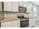 Contemporary kitchen boasts stainless steel appliances, granite counters, and sleek white cabinetry at 32231 Conchshell Sail St, Wesley Chapel, FL 33545