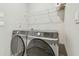 Modern laundry room features a front load washer and dryer and a white wire shelf at 32231 Conchshell Sail St, Wesley Chapel, FL 33545