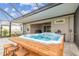 Covered patio with a blue hot tub on a wood base, complete with stools, and brick pavers at 32231 Conchshell Sail St, Wesley Chapel, FL 33545