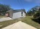 A view of the exterior side of the house with a driveway and grassy yard under a blue sky at 3308 E Frierson Ave, Tampa, FL 33610
