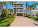 Stunning two-story home with a brick driveway and beautiful landscaping with palm trees against a clear blue sky at 443 18Th Ave, Indian Rocks Beach, FL 33785