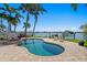 Beautiful kidney-shaped pool and spa with a dock on the water in the background at 443 18Th Ave, Indian Rocks Beach, FL 33785