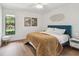 Cozy bedroom with a plush blue headboard bed, wood flooring, and ample natural light from the window at 48 Bishop Creek Dr, Safety Harbor, FL 34695