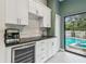 This kitchenette features white cabinets, stone backsplash, granite countertops, wine cooler, and access to the pool at 48 Bishop Creek Dr, Safety Harbor, FL 34695