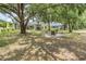 Large, landscaped backyard with mature trees, fire pit area, and screened-in porch offers space for outdoor activities at 5109 Hartwell Loop, Land O Lakes, FL 34638