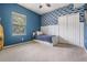 Stylish bedroom with blue accent wall and a bed with storage drawers, complemented by built-in closet and window at 5109 Hartwell Loop, Land O Lakes, FL 34638