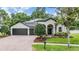 Charming single-story home features a brick driveway, a manicured lawn, and a three-car garage at 5109 Hartwell Loop, Land O Lakes, FL 34638