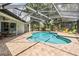 Backyard oasis featuring a sparkling pool, brick patio, screened enclosure, and lush landscaping at 5109 Hartwell Loop, Land O Lakes, FL 34638